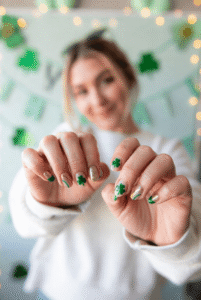 Girl showing cute St Patrick's Day Nail Designs with green and gold shamrock nail art for March celebration