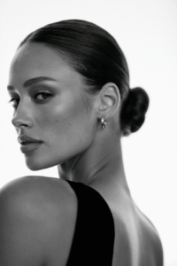 Woman with an elegant low bun hairstyle featuring soft face-framing strands and pearl hair accessories